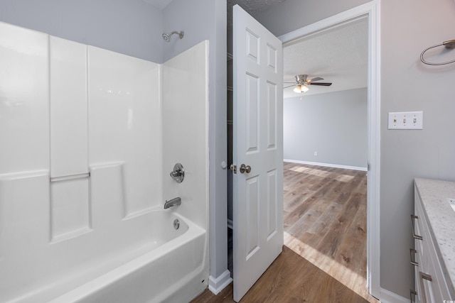 bathroom featuring shower / bathing tub combination, wood-type flooring, vanity, ceiling fan, and a textured ceiling