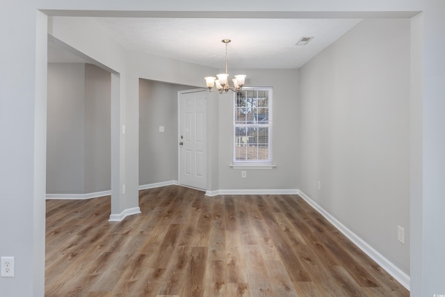 unfurnished dining area with an inviting chandelier and wood-type flooring