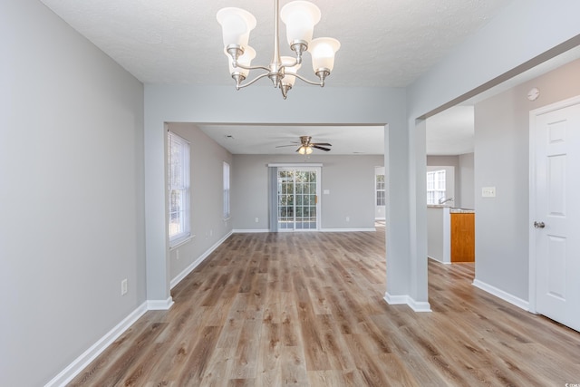 interior space with ceiling fan with notable chandelier, a textured ceiling, light hardwood / wood-style flooring, and a wealth of natural light