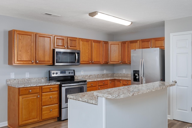 kitchen featuring appliances with stainless steel finishes, a center island, and wood-type flooring