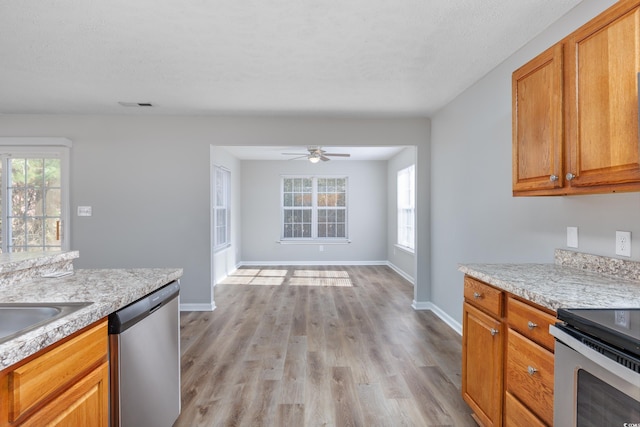 kitchen featuring light stone counters, appliances with stainless steel finishes, light hardwood / wood-style flooring, and a textured ceiling