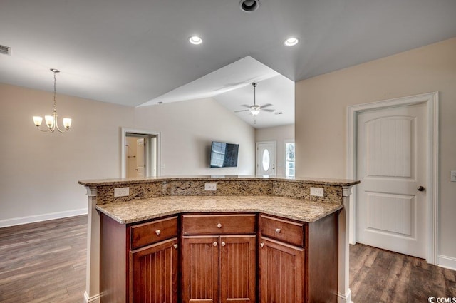 kitchen featuring dark wood-type flooring, lofted ceiling, a center island, hanging light fixtures, and ceiling fan with notable chandelier