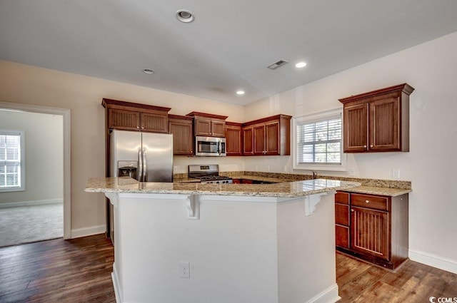 kitchen featuring a kitchen island, dark hardwood / wood-style flooring, appliances with stainless steel finishes, and a kitchen breakfast bar