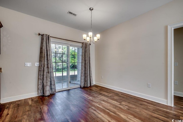 empty room featuring a chandelier and dark hardwood / wood-style flooring