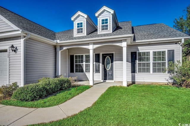 view of front of property featuring a garage, a front lawn, and a porch