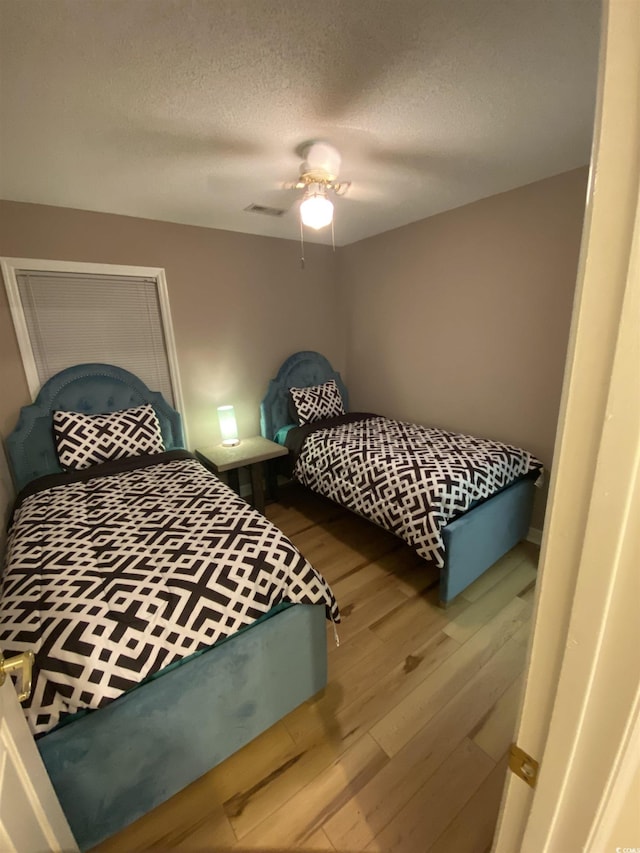 bedroom featuring ceiling fan, wood-type flooring, and a textured ceiling