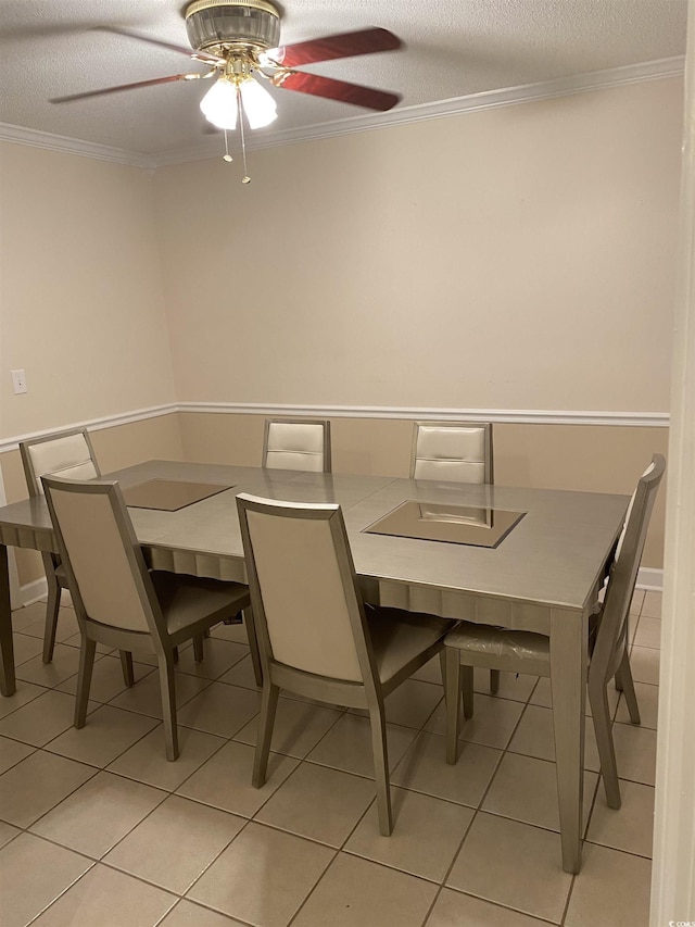 tiled dining area featuring ceiling fan, ornamental molding, and a textured ceiling