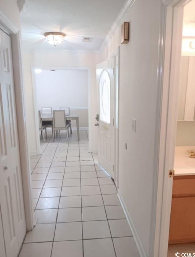 hallway with light tile patterned floors, crown molding, and sink