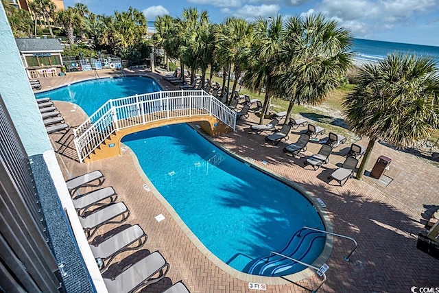 view of pool featuring a water view and a patio