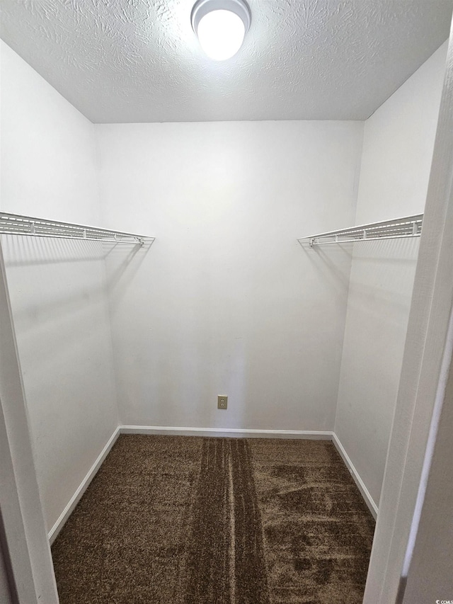 spacious closet featuring dark carpet