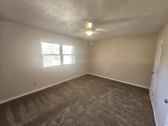 spare room featuring ceiling fan, dark carpet, and a textured ceiling