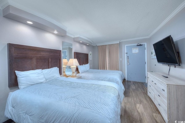 bedroom with a textured ceiling, light hardwood / wood-style floors, and crown molding