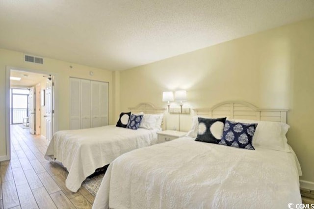 bedroom featuring light wood-type flooring, a textured ceiling, and a closet