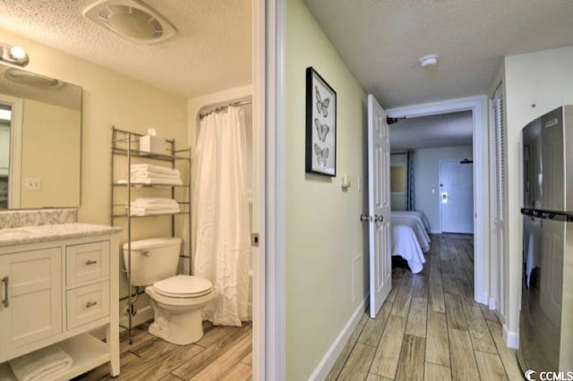 bathroom featuring hardwood / wood-style floors, a textured ceiling, and toilet