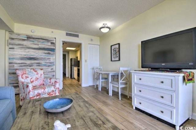 living room with a textured ceiling and light hardwood / wood-style flooring