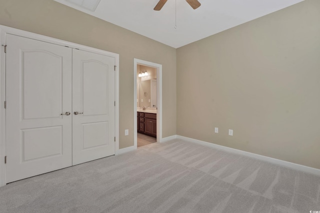 unfurnished bedroom with light carpet, ensuite bathroom, sink, ceiling fan, and a closet