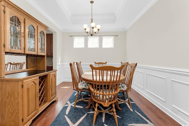 dining space featuring a notable chandelier, crown molding, dark wood-type flooring, and a tray ceiling