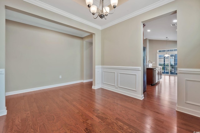 spare room with ornamental molding, dark wood-type flooring, a notable chandelier, and sink