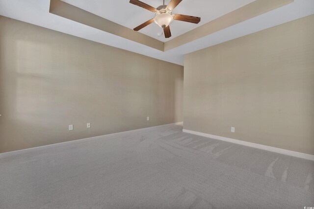 spare room featuring carpet flooring, ceiling fan, and a raised ceiling