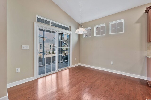 unfurnished dining area with vaulted ceiling and hardwood / wood-style flooring