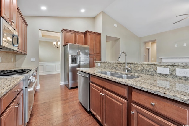 kitchen featuring light stone countertops, appliances with stainless steel finishes, light hardwood / wood-style floors, and sink