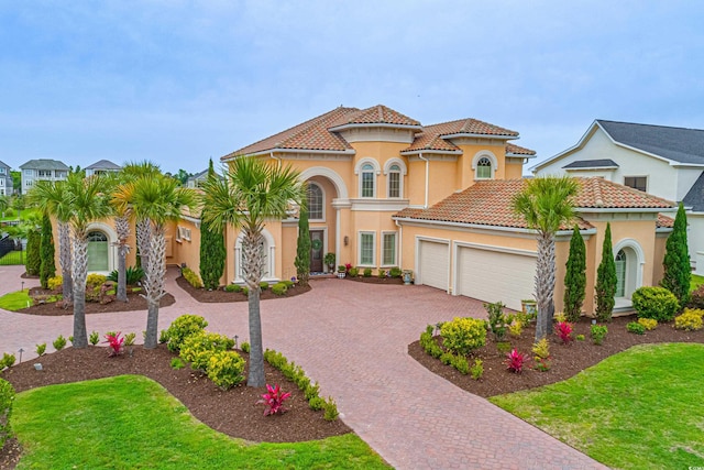 mediterranean / spanish home with stucco siding, a tile roof, decorative driveway, and a garage