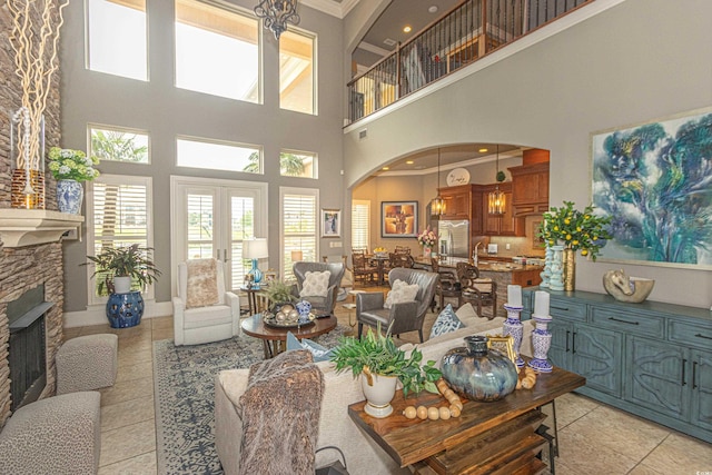 living room with arched walkways, a fireplace, crown molding, and light tile patterned flooring