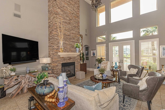 tiled living area featuring visible vents, baseboards, a stone fireplace, french doors, and arched walkways