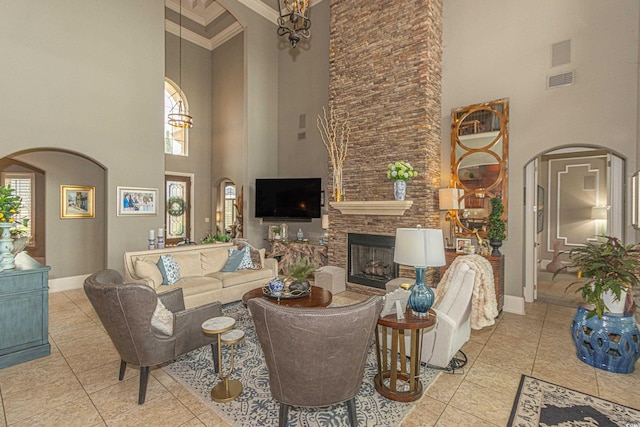 living room featuring baseboards, arched walkways, a stone fireplace, tile patterned floors, and a wealth of natural light