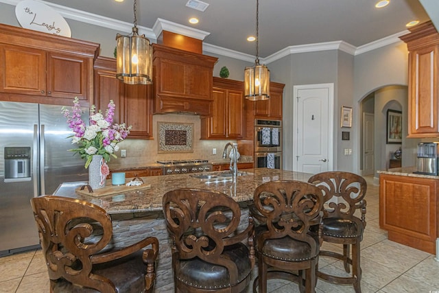 kitchen with tasteful backsplash, brown cabinets, arched walkways, stainless steel appliances, and a sink