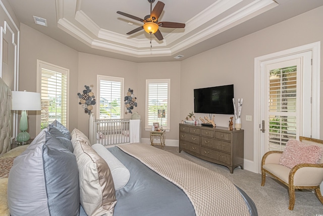 carpeted bedroom with a tray ceiling, crown molding, visible vents, and baseboards