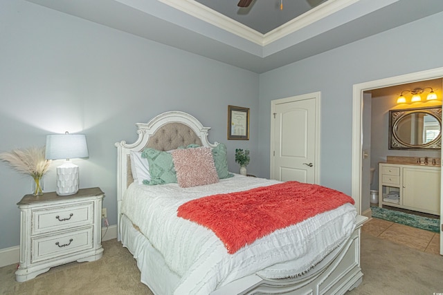 bedroom featuring light colored carpet, a tray ceiling, ornamental molding, ensuite bathroom, and a sink