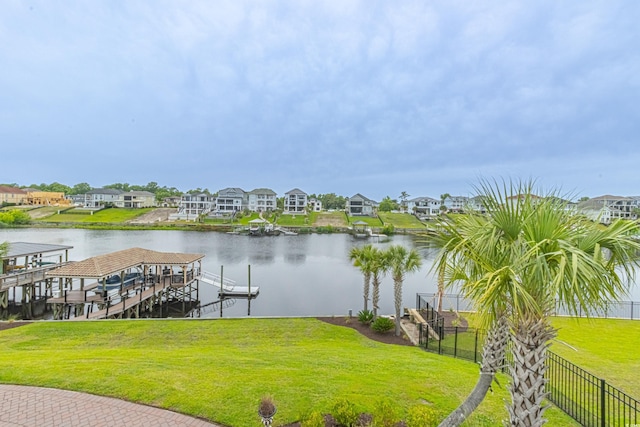 view of dock with a yard, a residential view, fence, and a water view