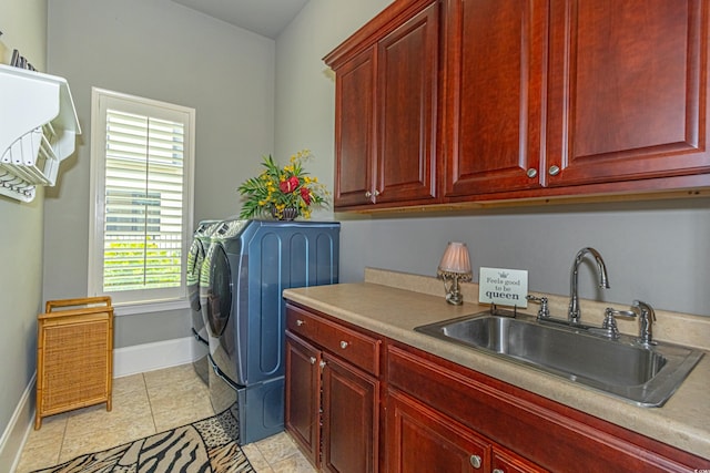 washroom featuring a sink, cabinet space, separate washer and dryer, light tile patterned floors, and baseboards