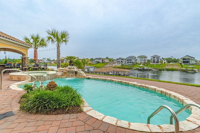 view of pool with a patio area, a residential view, a pool with connected hot tub, and a water view