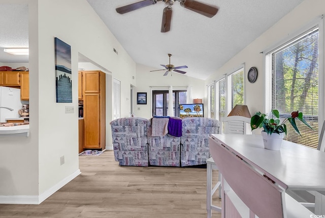 living room with light wood-style floors, a ceiling fan, a textured ceiling, and lofted ceiling