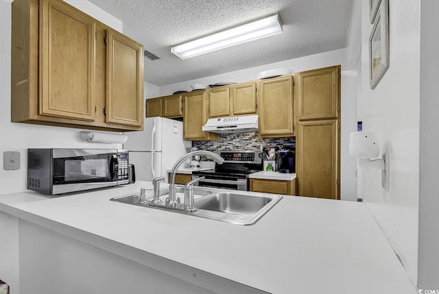 kitchen featuring light countertops, under cabinet range hood, tasteful backsplash, a sink, and stainless steel appliances