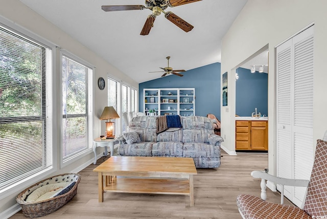 living area featuring vaulted ceiling, light wood-style floors, and a ceiling fan