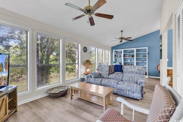 living area with baseboards, ceiling fan, vaulted ceiling, and wood finished floors