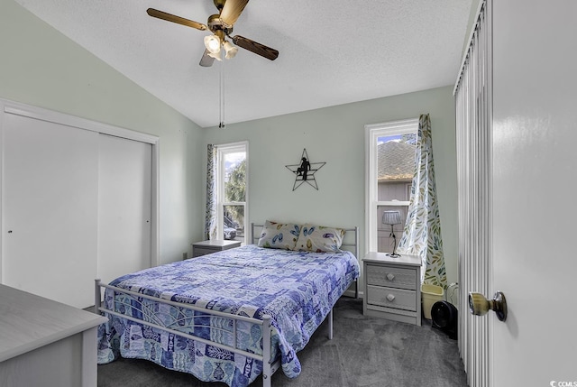 bedroom with ceiling fan, dark carpet, a textured ceiling, and vaulted ceiling