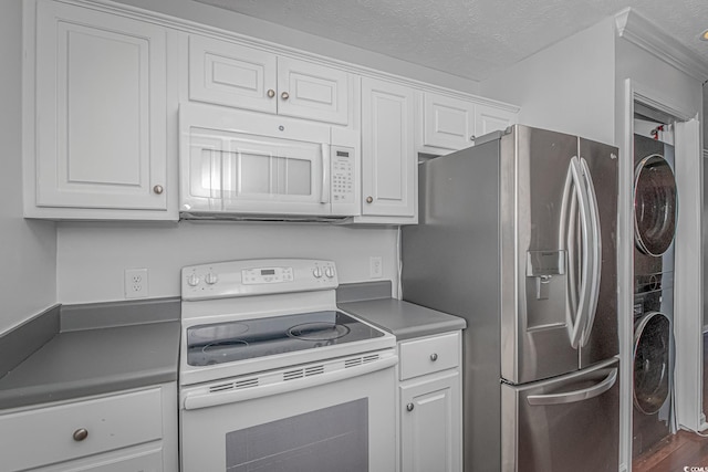 kitchen featuring a textured ceiling, white appliances, white cabinetry, stacked washer / drying machine, and dark countertops