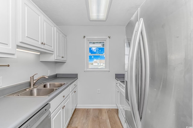 kitchen with baseboards, appliances with stainless steel finishes, light wood-style floors, white cabinetry, and a sink