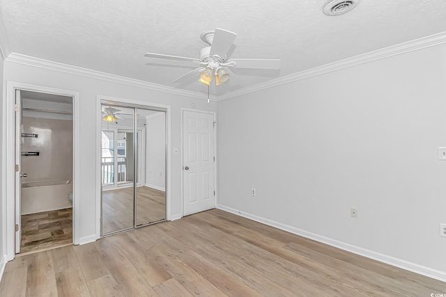 unfurnished bedroom with light wood-style flooring, ornamental molding, and a textured ceiling