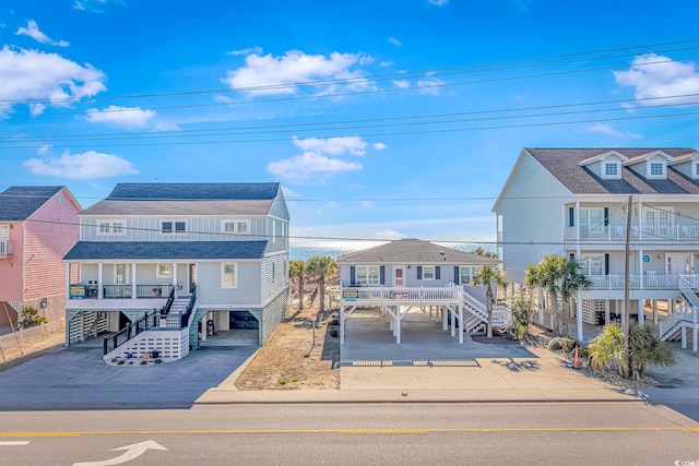 raised beach house featuring driveway, stairway, and a carport