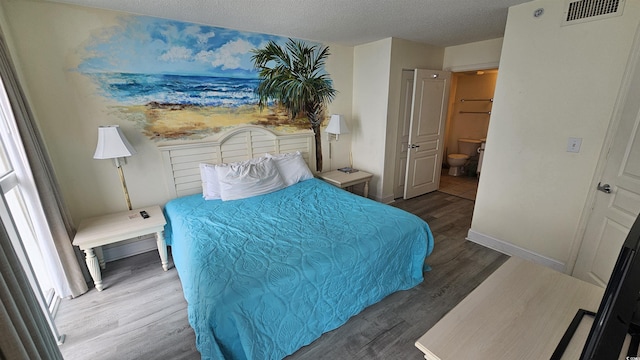 bedroom with a textured ceiling, dark wood-type flooring, and connected bathroom