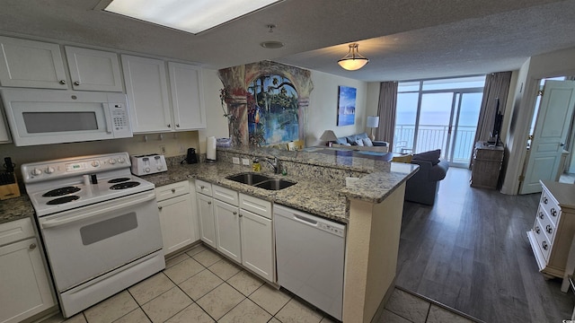 kitchen featuring white cabinetry, sink, a wall of windows, kitchen peninsula, and white appliances