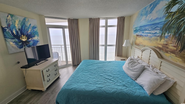 bedroom with access to exterior, multiple windows, hardwood / wood-style flooring, and a wall of windows