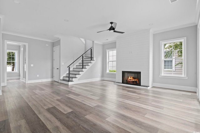 unfurnished living room with ornamental molding, a fireplace, light wood-type flooring, and plenty of natural light