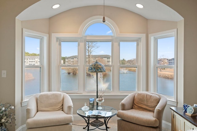 sitting room with a water view and lofted ceiling