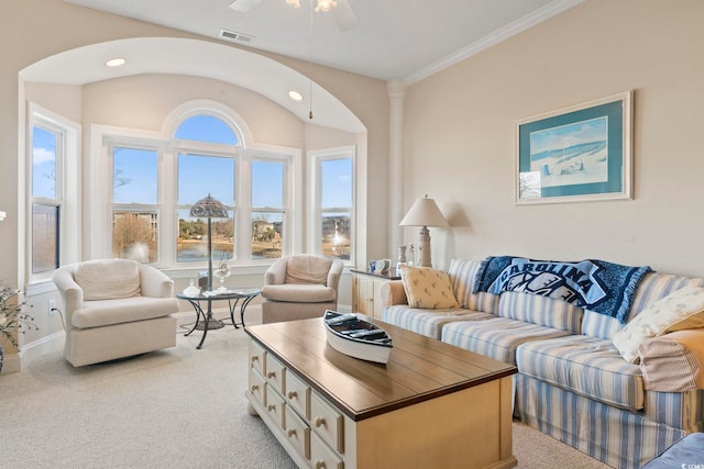 living room with ceiling fan, crown molding, and light colored carpet